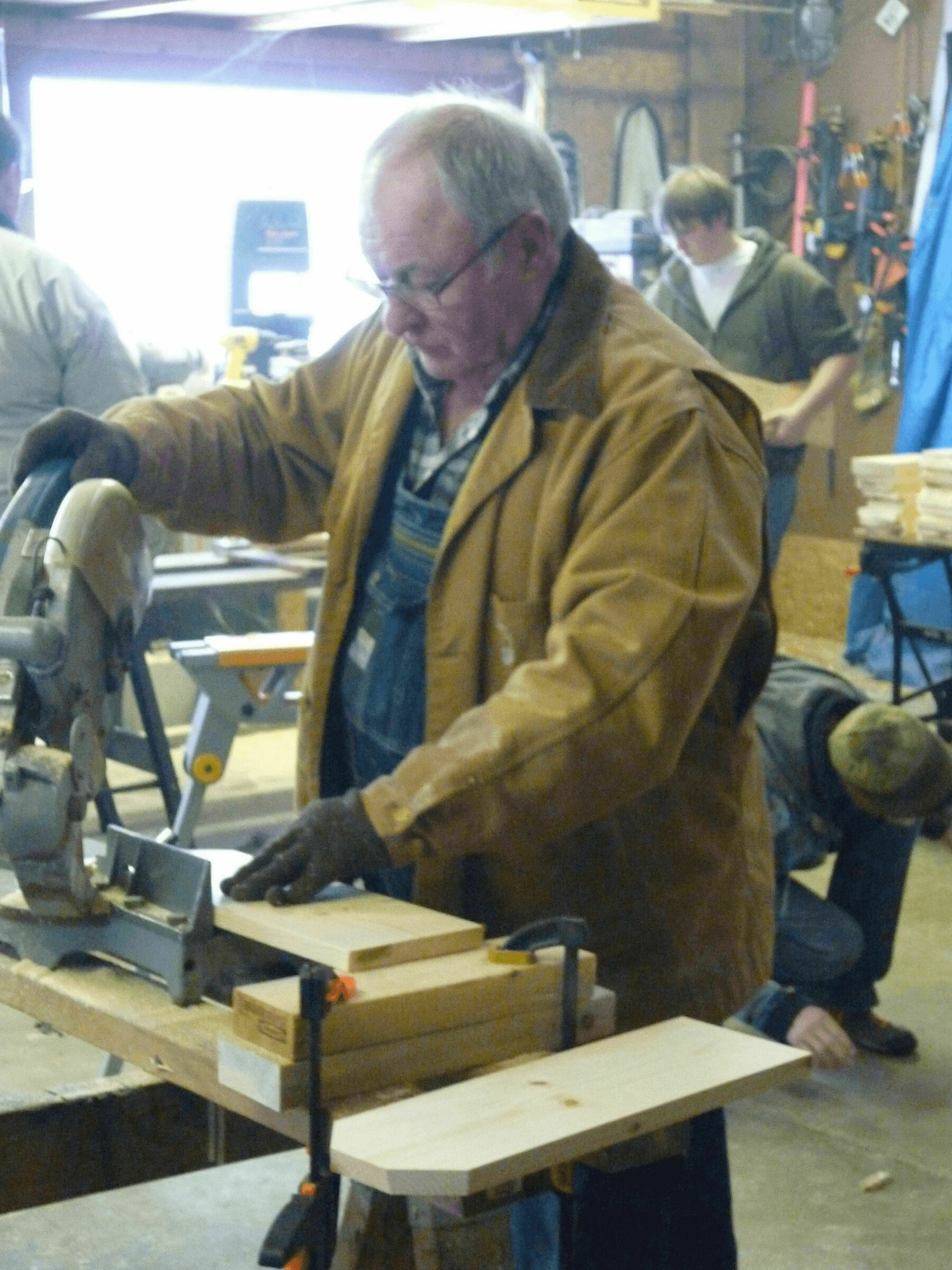 My grandpa cutting wood on a circular saw in a garage.